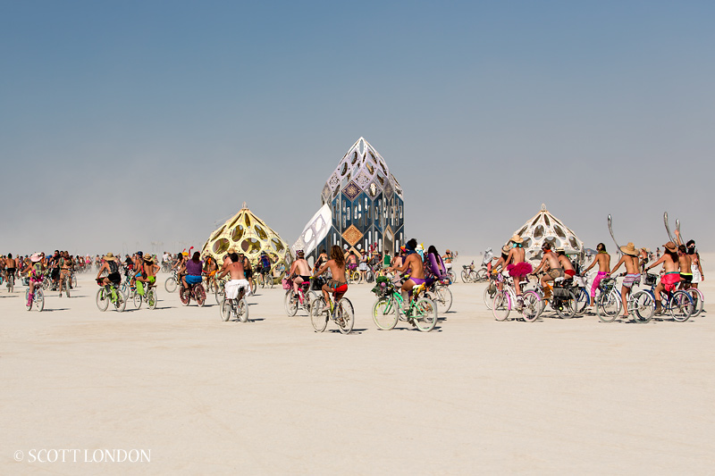 Burners ride their bikes past Zonotopia, an installation by Rob Bell, at Burning Man 2013 (Photo by Scott London)