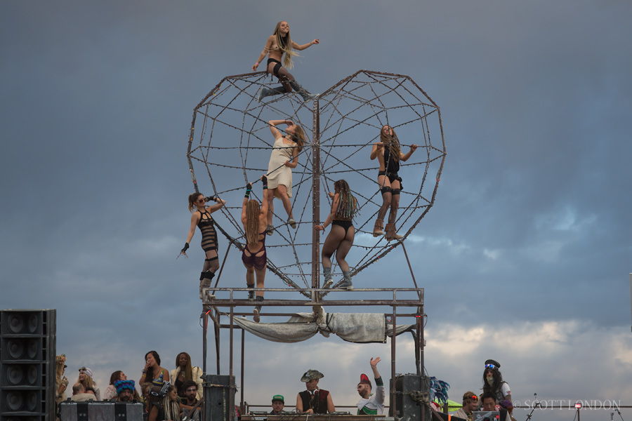 Women dance on a giant metal heart on top of the Robot Heart bus at Burning Man 2016