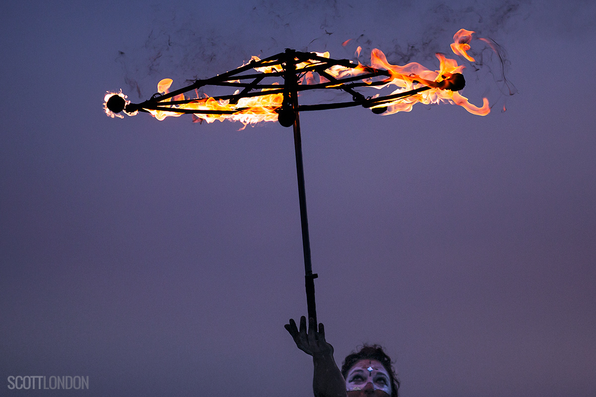 Sara performs with a burning umbrella in the early morning twilight at Burning Man 2017. (Photo by Scott London)