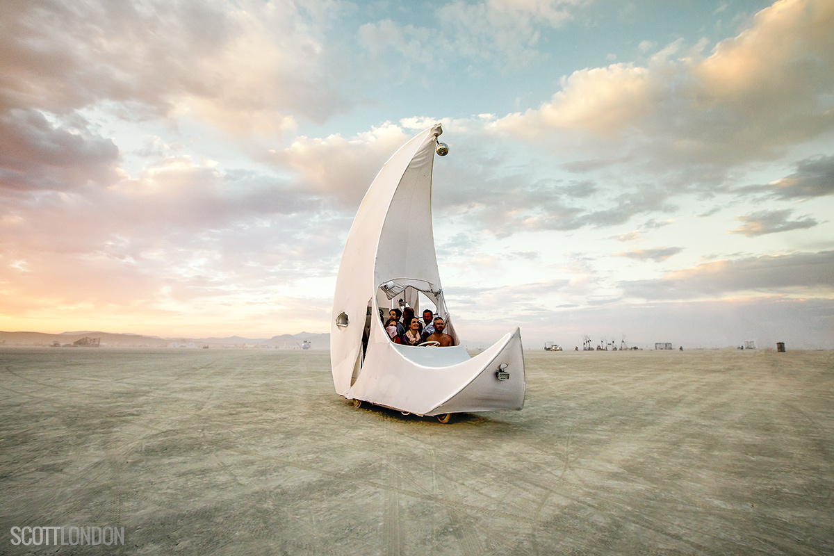 Friends ride around at sunset in a crescent-shaped art car. (Photo by Scott London)
