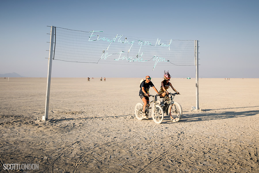 A couple ride their bikes under an installation by Olivia Steele at Burning Man 2017. (Photo by Scott London)