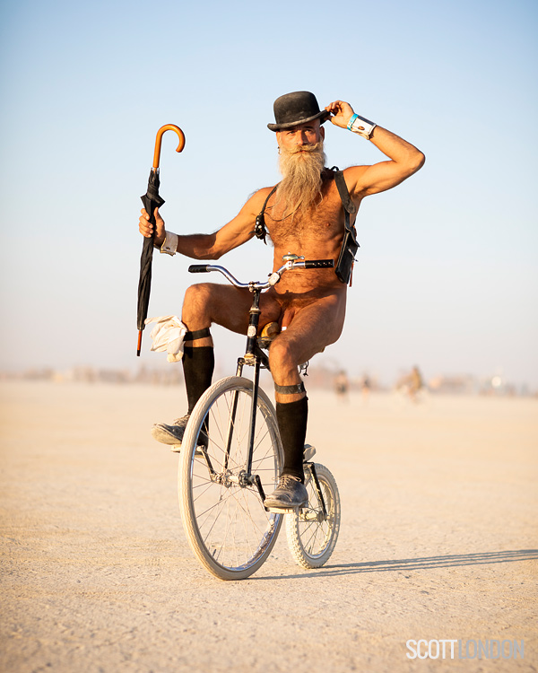 Sporting a top hat and umbrella, Randal rides a penny farthing at Burning Man 2018. (Photo by Scott London)