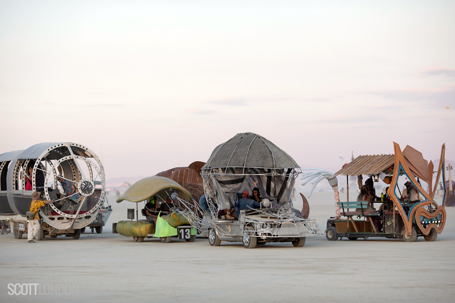 A fleet of art cars wait in line for their licensing inspection at the Department of Mutant Vehicles (DMV) at Burning Man 2018. (Photo by Scott London)