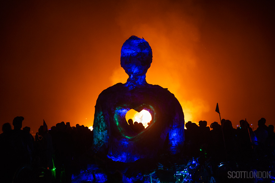 Thousands gather for the temple burn on the second-to-last night of Burning Man 2018, seen here silhouetted with the Open Hearted Meditator, an art installation by Swig Miller. (Photo by Scott London)