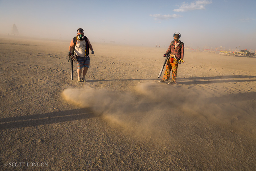 Two performance artists clear dust and debris after a day of high winds at Burning Man 2015. (Photo by Scott London)